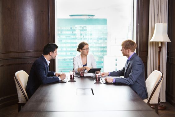 business-people-sitting-large-wooden-table-with-laptop